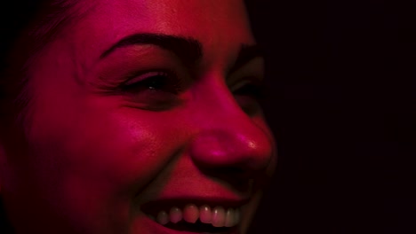 Woman-laughing-while-watching-a-screen-either-tv-or-cinema-while-lit-by-rgb-light