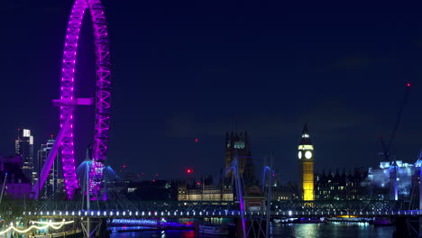 Night-time-lapse-of-River-Thames-and-London-Eye-from-Waterloo-bridge,-London-Eye-with-bright-purple-ligths,-tourists-in-south-bank-and-rive-traffic
