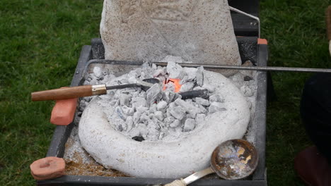 Close-up-of-a-small-forge-with-glowing-embers,-blacksmith-tools,-and-anvil,-showcasing-traditional-metalwork