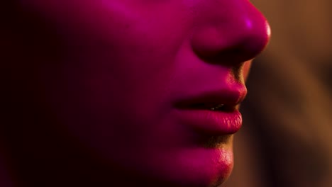 Woman-flinches-and-reacts-close-up-on-mouth-lit-by-multiple-colours