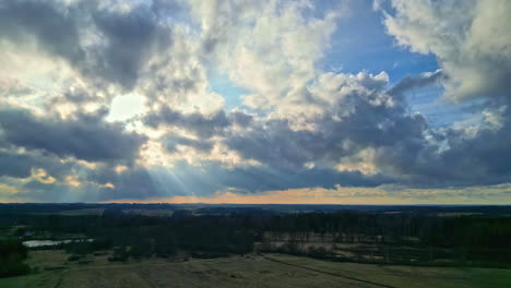 Drone-fly-above-agricultural-fields-with-sun-shining-through-morning-clouds-sky-shining-background,-hopeful-landscape,-meadows