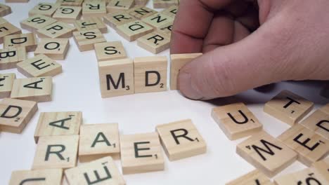 On-white-table-top,-hand-forms-drug-acronym-MDMA-with-Scrabble-tiles