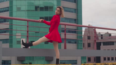 On-a-rooftop-in-Port-of-Spain,-Trinidad,-a-young-Hispanic-girl-elegantly-stands-in-a-red-dress,-tall-buildings-framing-the-scene