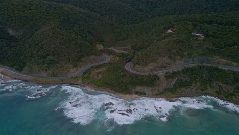 Australia's-Great-Ocean-Road-orbit-drone-shot-showing-curved-highway-with-crashing-coastal-surf-in-Victoria
