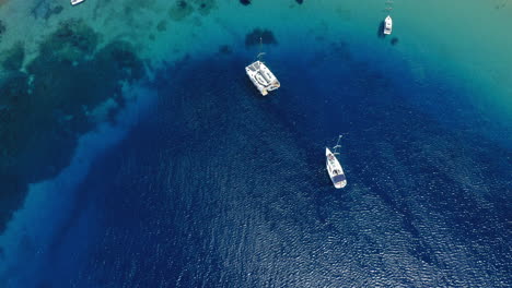 Aerial:-Reveal-shots-of-Sailboats-and-catamarans-on-Tsougria-island-beach-near-Skiathos,-Sporades,-Greece