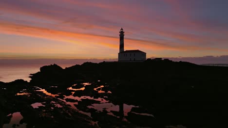 Toma-Aérea-Del-Faro-De-Favaritx-Menorca-Hito-Histórico-Horizonte-Del-Atardecer-En-El-Entorno-Costero-Natural