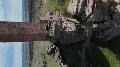 Approaching-drone-aerial-view,-vertical-mode,-to-the-main-tower-of-a-medieval-castle-built-in-the-top-of-a-rocky-hill