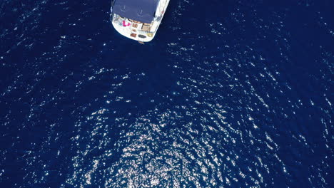 Aerial:-Top-down-drone-shot-of-a-sailboat-in-blue-sea
