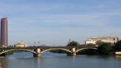 Autos-Fahren-Durch-Die-Puente-De-Triana-Mit-Dem-Triana-Turm-Und-Dem-Sevilla-Turm-Im-Hintergrund-In-Sevilla,-Spanien