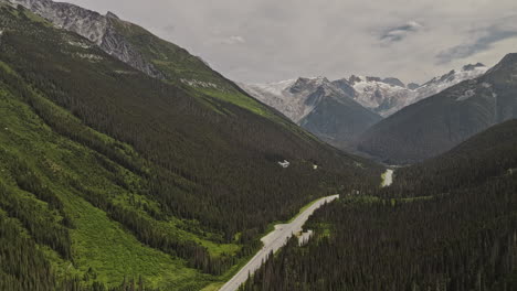 Rogers-Pass-BC-Canada-Aerial-v4-drone-flyover-Trans-Canada-highway-capturing-lush-forested-valley,-Selkirk-mountain-ranges-and-Youngs-peak-in-the-background---Shot-with-Mavic-3-Pro-Cine---July-2023