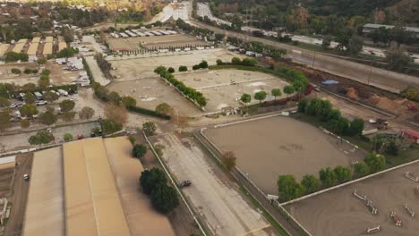 Toma-Aérea-Establecida,-Dron-Mirando-Hacia-El-Centro-Ecuestre-De-Los-Ángeles-Durante-El-Día,-Autopista-A-La-Derecha-Y-Campos-De-Entrenamiento-Debajo.