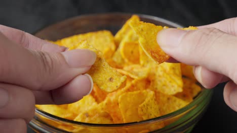 Tortilla-chips-being-sliced-breaking-by-caucasian-male-white-hands-closeup-food-mexican-style-snack-dish
