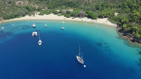 Aerial:-Slow-orbit-drone-shot-of-Tsougria-island-beach-near-Skiathos,-Sporades,-Greece-with-turquoise-and-emerald-crystal-clear-water