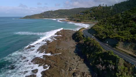 White-truck-drives-along-rocky-Great-Ocean-Road-coastline-at-Wye-River-on-sunny-day-in-Victoria,-Australia