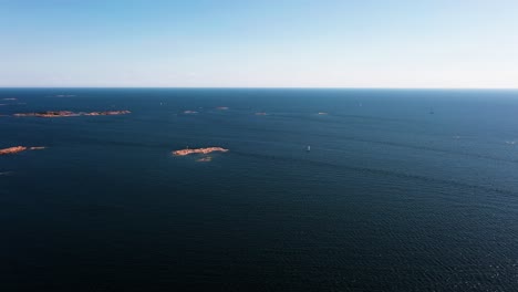 Aerial-view-away-from-a-sailboat-sailing-in-middle-of-rocky-isles,-on-the-Gulf-of-Finland