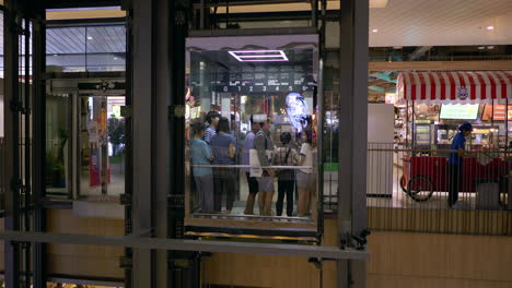 Shoppers-and-moviegoers-going-down-to-the-next-floor-through-and-elevator-in-a-shopping-mall-in-Bangkok,-Thailand