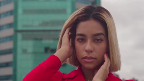 In-Port-of-Spain,-Trinidad,-a-young-girl-of-Hispanic-descent,-clad-in-a-red-dress,-stands-on-a-rooftop-with-tall-buildings-in-the-backdrop-close-up