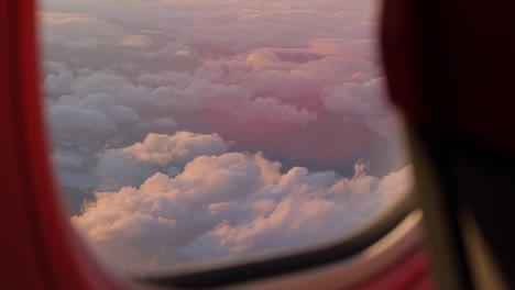 The-airplane-window-offers-a-scenic-vista-of-sunlit-clouds,-casting-a-serene-glow,-symbolizing-the-essence-of-travel-and-vacation