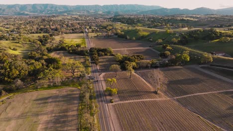 Aerial-Footage-Over-Country-Road-in-Santa-Ynez-California,-Wine-Country-Farmland-as-Seen-from-the-Sky,-Mountain-Range-on-Horizon