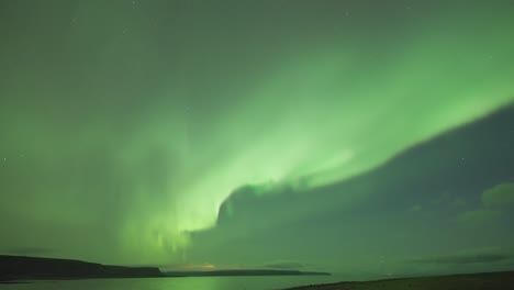 Ein-Zeitraffervideo-Der-Faszinierenden-Nordlichter,-Die-In-Einer-Dunklen-Winternacht-über-Einem-Ruhigen-Fjord-Tanzen