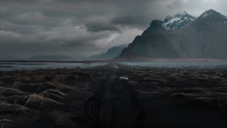 Drone-footage-over-Stokksnes-black-sand-beach,-showcasing-dramatic-clouds-and-the-majestic-Vestrahorn-mountain,-Iceland