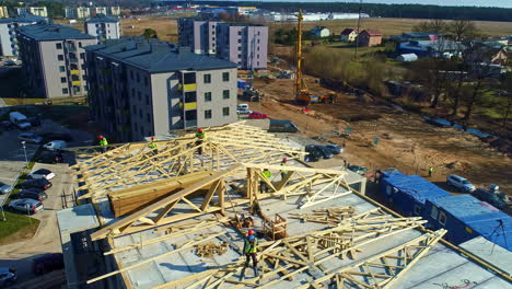 Aerial-view-of-workers-building-wooden-roof-carcass-on-multi-storey-apartment-building