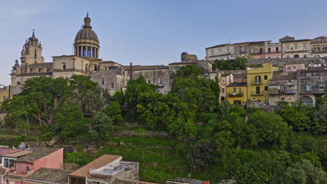 Ragusa-Italy-Aerial-v8-elevated-shot-capturing-charming-residential-townhouses-of-Ibla-town,-followed-by-a-tilt-down-bird's-eye-view-above-Cathedral-of-San-Giorgio---Shot-with-Mavic-3-Cine---June-2023
