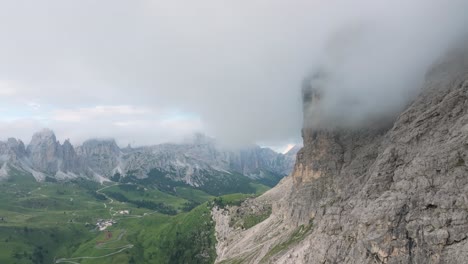 Cinematic-aerial-footage,-Corvara-town-emerges-against-the-rugged-Dolomites-backdrop-in-Passo-Gardena