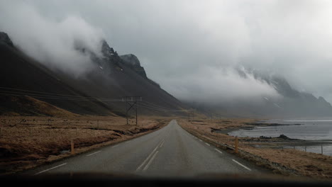 Driving-along-Route-1-in-Northern-Iceland,-featuring-expansive-views-of-mountains,-clouds,-and-coastal-landscapes-with-grass