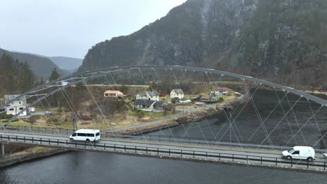 White-minibus-with-tourists-passing-old-steel-bridge-at-Stamneshella-in-early-spring-season,-Aerial