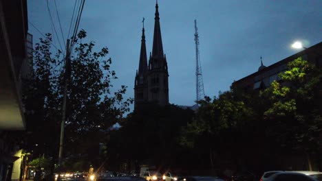 Horizonte-De-La-Ciudad-En-La-Noche-Basílica-Nuestra-Señora-De-Buenos-Aires-Torre-Alta-Sobre-Cielo-Azul-Autos-Conduciendo-Por-Carril-Rápido-Nocturno,-Ciudad-Metropolitana-Latina-Punto-De-Referencia-Religioso