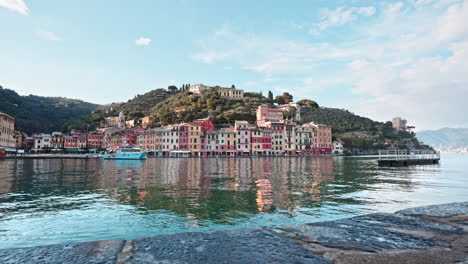 Blue-tourist-ferry-boat-docking-at-small-Portofino-harbor-with-colorful-houses