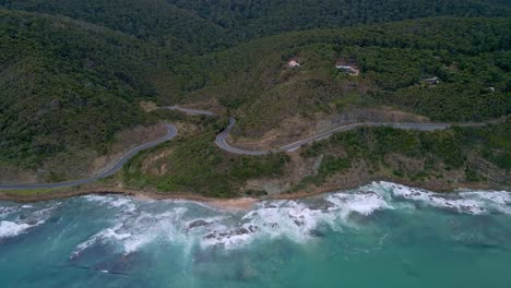 Wide-aerial-view-of-Australia's-Great-Ocean-Road-with-curved,-winding-highway-turns-and-dense-forest,-Victoria