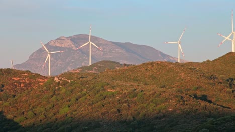 Idyllic-landscape-of-mountainous-Aegean-Turkey-and-quickly-rotating-blades-of-wind-power-turbine-plants-among-sunlit-hills,-Datça-peninsula