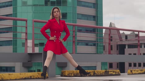 In-Port-of-Spain,-Trinidad,-a-young-Hispanic-girl-sits-on-a-rooftop-in-a-red-dress,-with-tall-buildings-in-the-distance