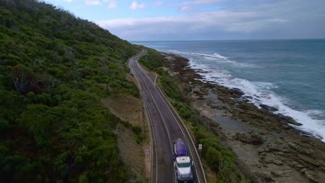 Cement-construction-truck-drives-along-Great-Ocean-Road-in-Victoria,-Australia---aerial-view