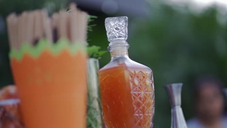Glass-decanter-with-orange-liquid-on-counter-in-outdoor-party-bar