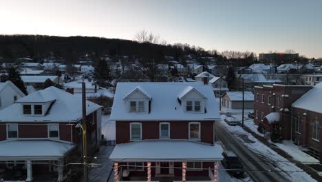 Snow-covered-town-house-with-Christmas-lights-on-front-porch