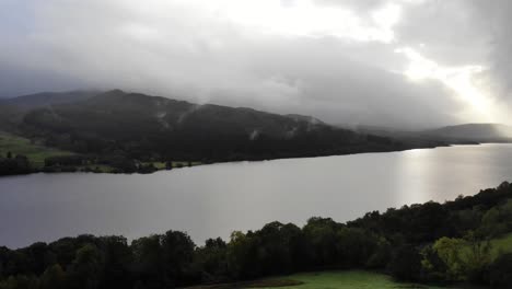 Toma-Panorámica-Hacia-La-Derecha-Que-Revela-La-Longitud-Del-Lago-Tummel-En-Las-Tierras-Altas-De-Escocia-Con-El-Sol-Atravesando-Las-Nubes.