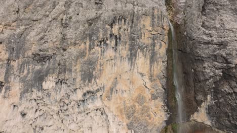 Cinematic-ascending-aerial-view-of-the-Murfreit-waterfall-near-Passo-Gardena