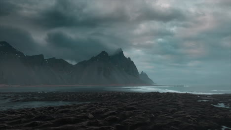 Drohnenaufnahmen-über-Dem-Schwarzen-Sandstrand-Von-Stokksnes-Mit-Dramatischen-Wolken-Und-Dem-Majestätischen-Berg-Vestrahorn,-Island