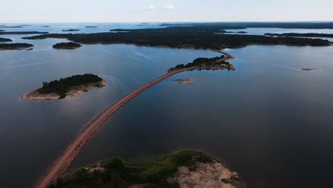 Aerial-view-circling-a-narrow-road-with-a-car,-linking-islands-in-Aland,-Finland