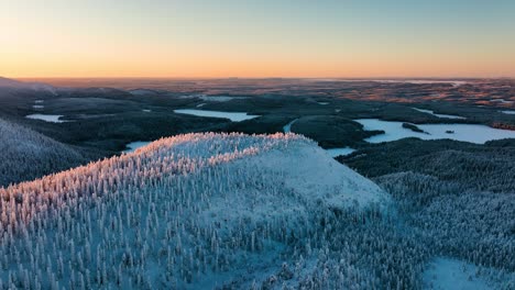 Aerial-view-of-a-snowy-landscape-with-fells-and-arctic-wilderness,-sunset-in-Lapland