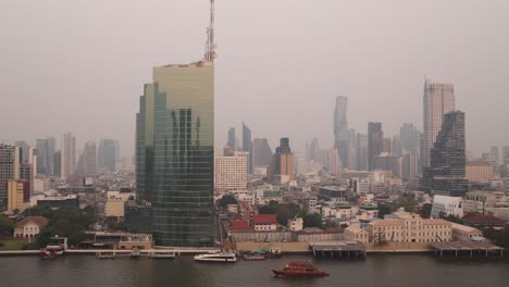 Boote-Fahren-Bei-Sonnenuntergang-Den-Fluss-Chao-Phraya-Hinunter-Mit-Skyline-In-Der-Innenstadt-Von-Bangkok,-Der-Hauptstadt-Thailands