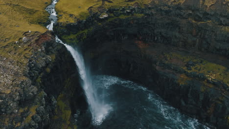 Mulafossur-waterfall,-Faroe-Islands:-fantastic-aerial-view-looking-away-from-the-beautiful-waterfall-and-the-wind-hitting-the-water