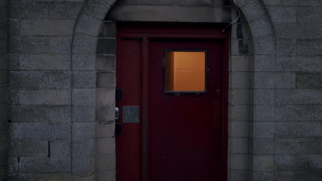 Red-metal-entrance-door-in-a-cinder-block-house-in-a-moody-cinematic-look