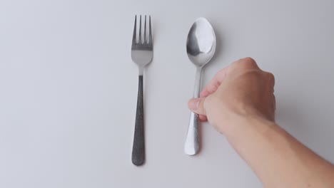 Fork-and-spoon-being-placed-on-a-white-background