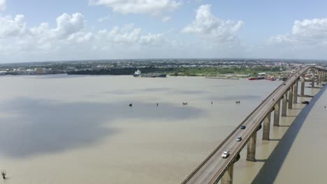Wide-angle-aerial-shot-of-Jules-Wijdenbosch-Bridge-between-Paramaribo-and-Meerzorg-in-Suriname,-South-America,-with-traffic-as-drone-gains-backwards