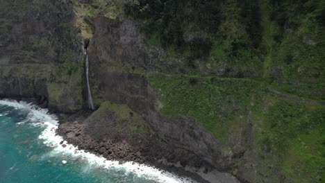 Wellen,-Die-An-Die-Felsige-Küste-Der-Insel-Madeira-Mit-Wasserfall-In-Portugal-Krachen