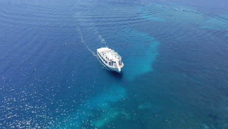 Aérea:-Toma-En-órbita-Lenta-De-Un-Crucero-Que-Se-Mueve-Lentamente-Sobre-Aguas-Poco-Profundas-De-Color-Turquesa-Y-Azul-Claro